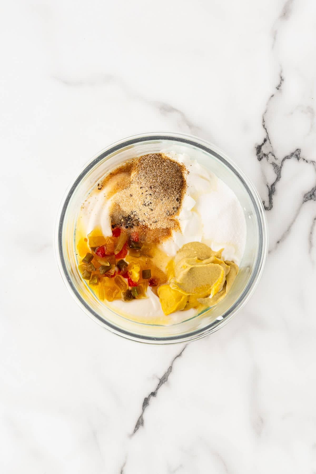 Bowl of dressing ingredients with mayo, mustard, relish, and spices