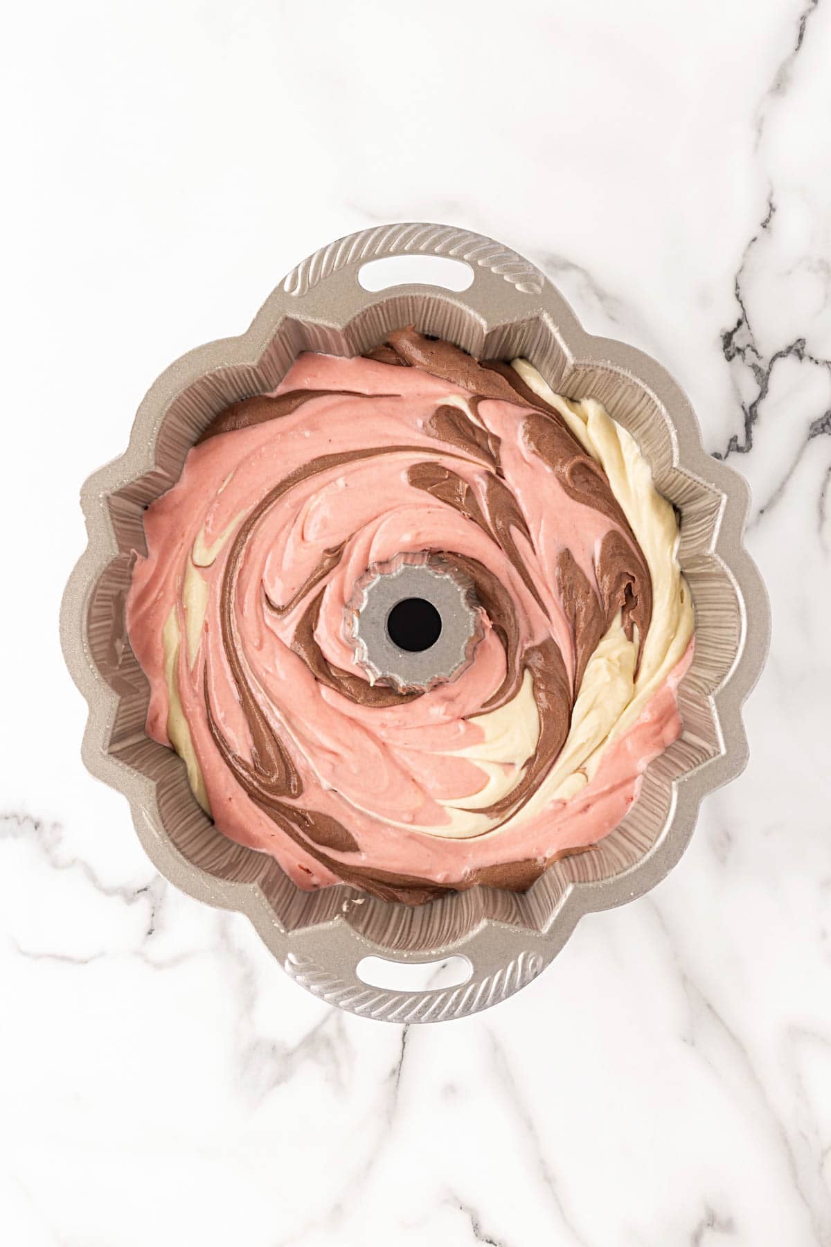 Swirled Neapolitan cake batter layered in a Bundt pan before baking