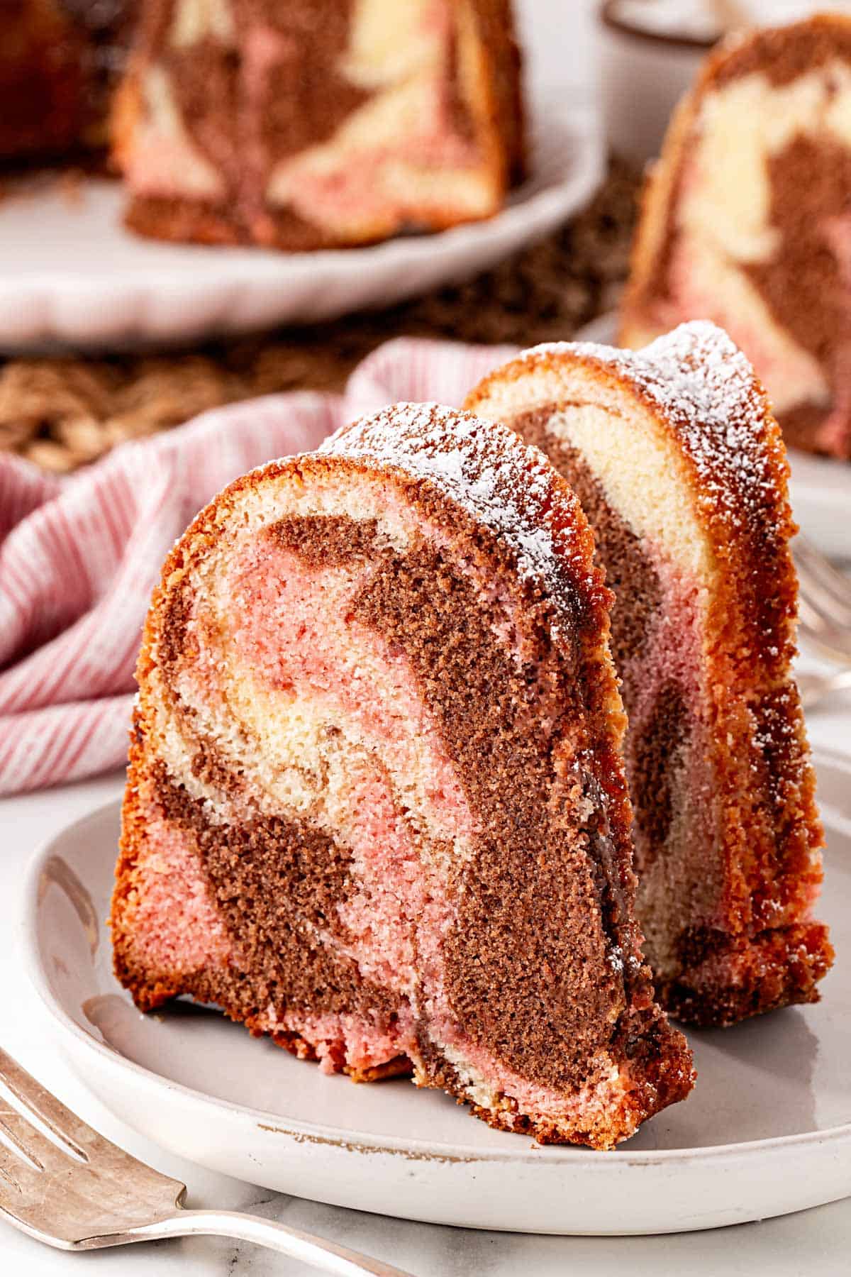 Slices of Neapolitan pound cake with chocolate, vanilla, and strawberry swirls on a plate