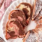 Overhead shot of sliced Neapolitan pound cake dusted with powdered sugar on a serving platter