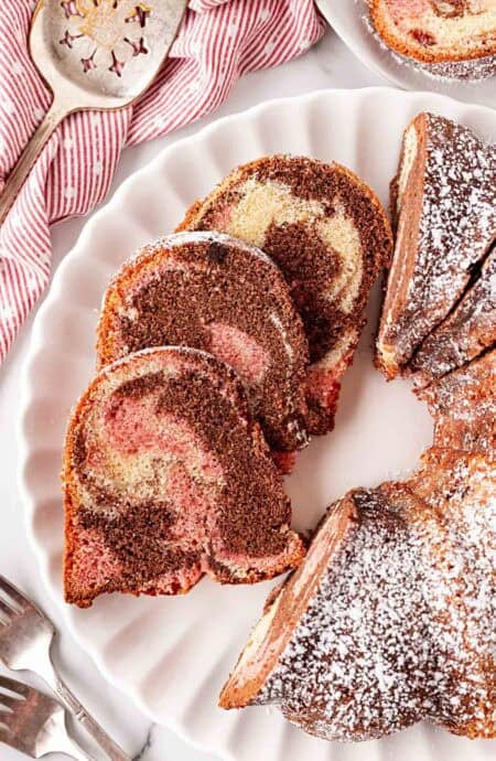 Overhead shot of sliced Neapolitan pound cake dusted with powdered sugar on a serving platter