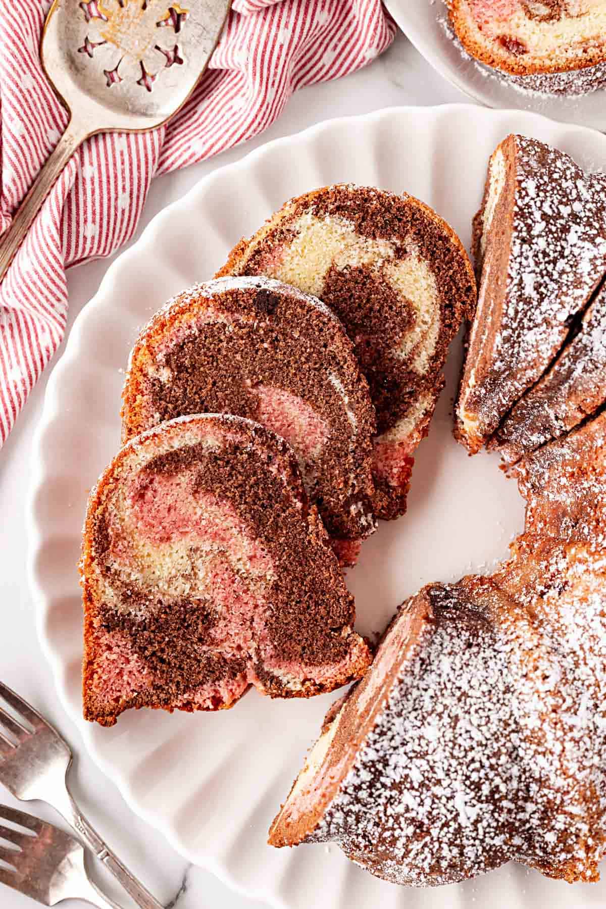 Overhead shot of sliced Neapolitan pound cake dusted with powdered sugar on a serving platter