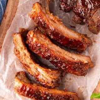 Overhead shot of oven baked ribs sliced and brushed with sauce on parchment paper