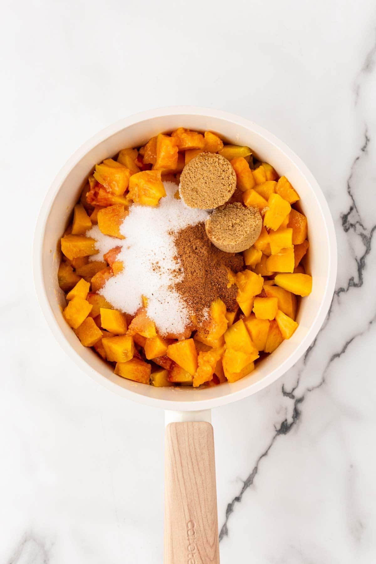 Chopped peaches with sugar and cinnamon in saucepan