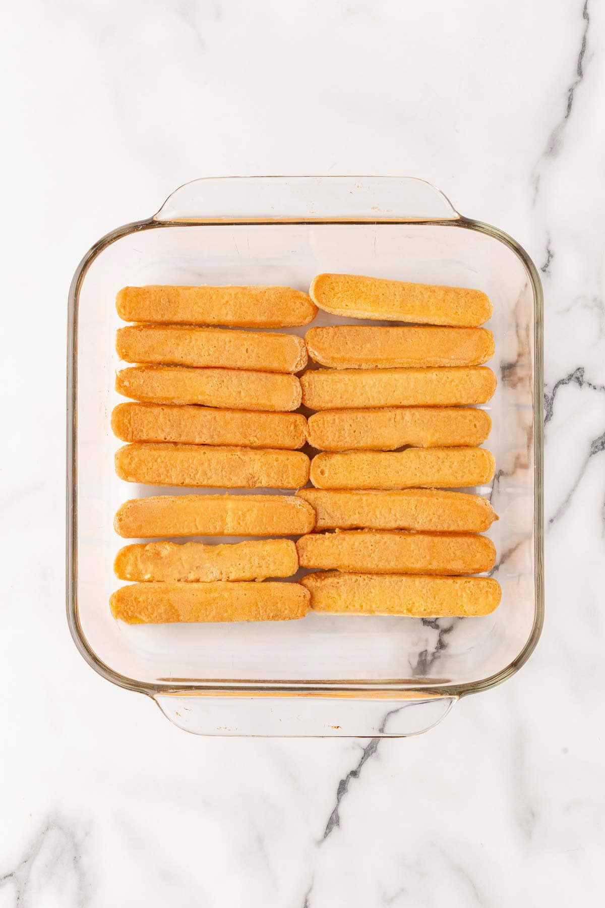 Layer of ladyfingers in square glass baking dish