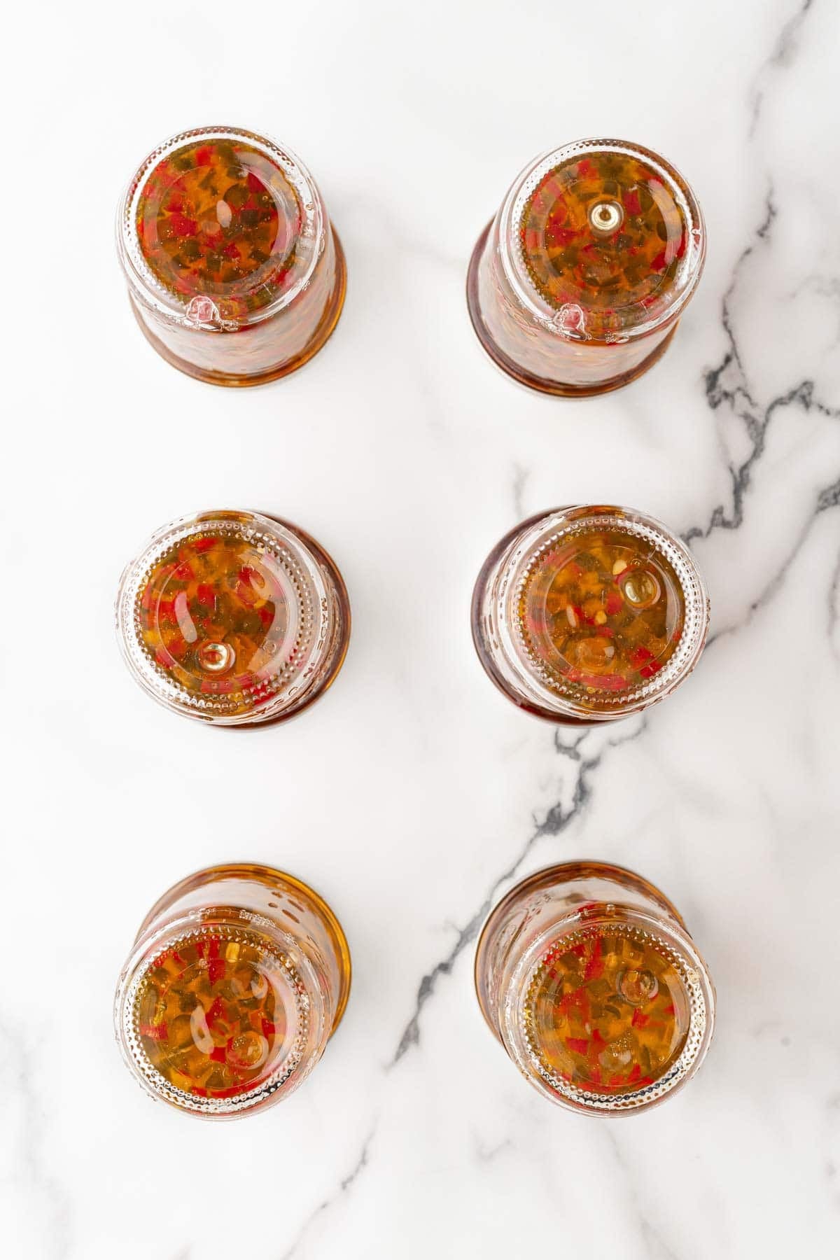 Upside-down mason jars filled with pepper jelly cooling on a countertop