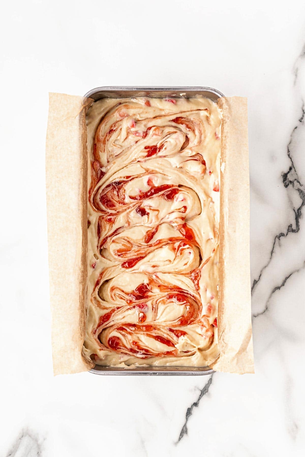 Strawberry batter swirled in lined loaf pan