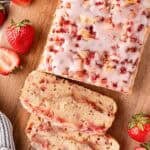 Sliced strawberry bread loaf on wooden board with fresh strawberries