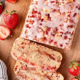Sliced strawberry bread loaf on wooden board with fresh strawberries