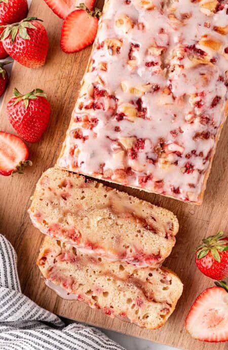 Sliced strawberry bread loaf on wooden board with fresh strawberries