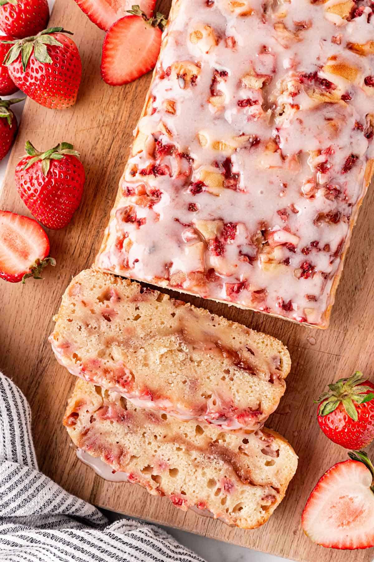 Sliced strawberry bread loaf on wooden board with fresh strawberries