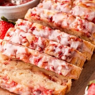 Sliced strawberry bread loaf on wooden board with fresh strawberries