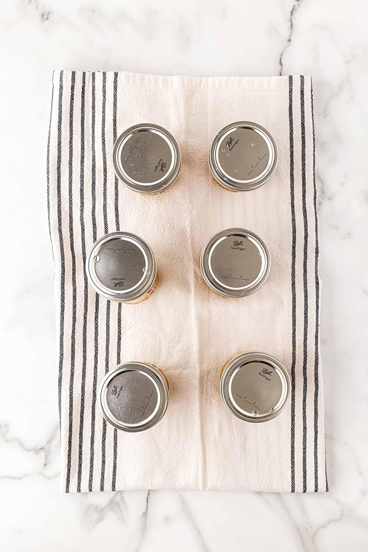 Sealed jars of chow chow relish cooling on a kitchen towel