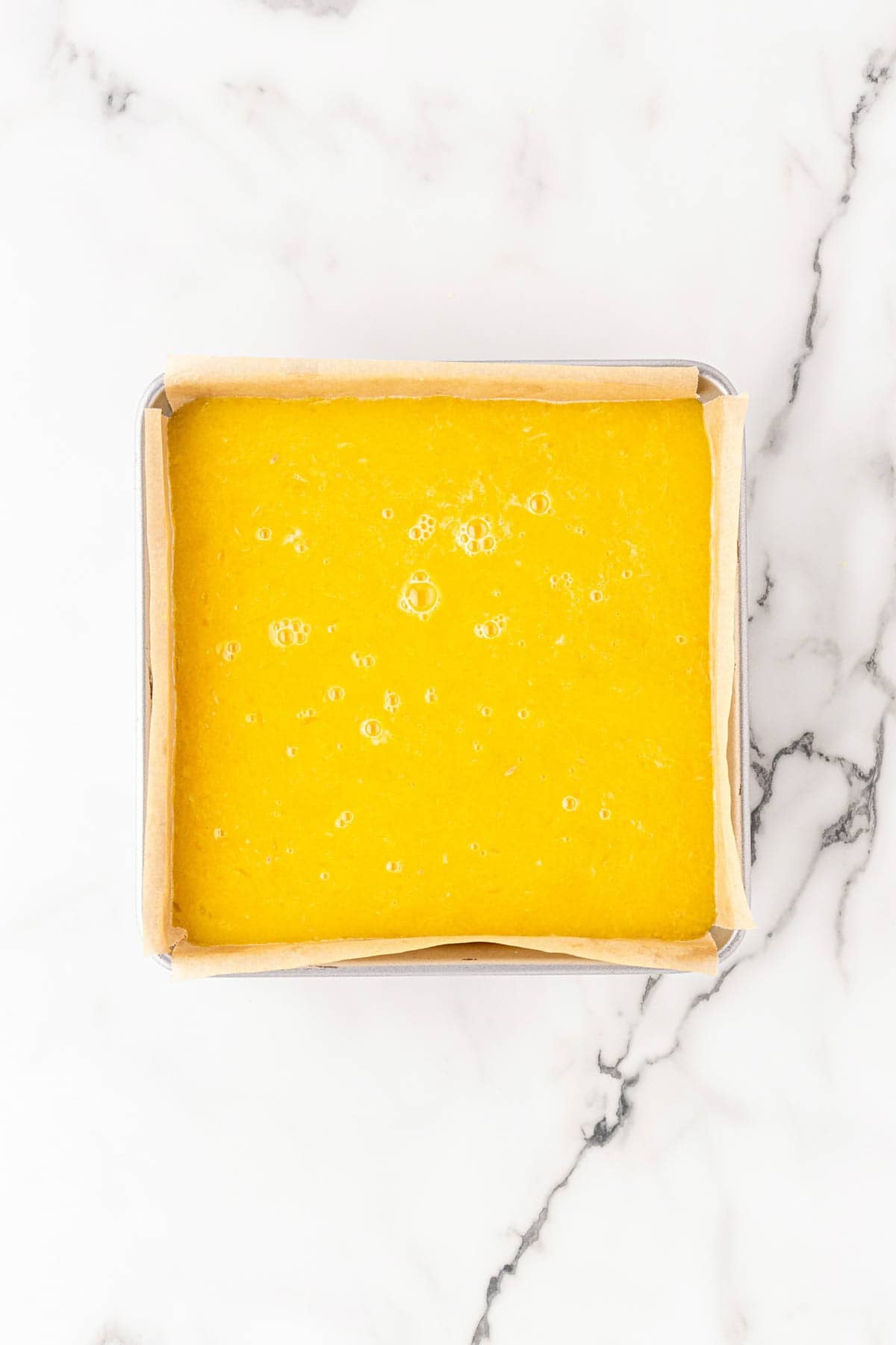 Bright lemon filling poured over the baked crust in a square baking pan