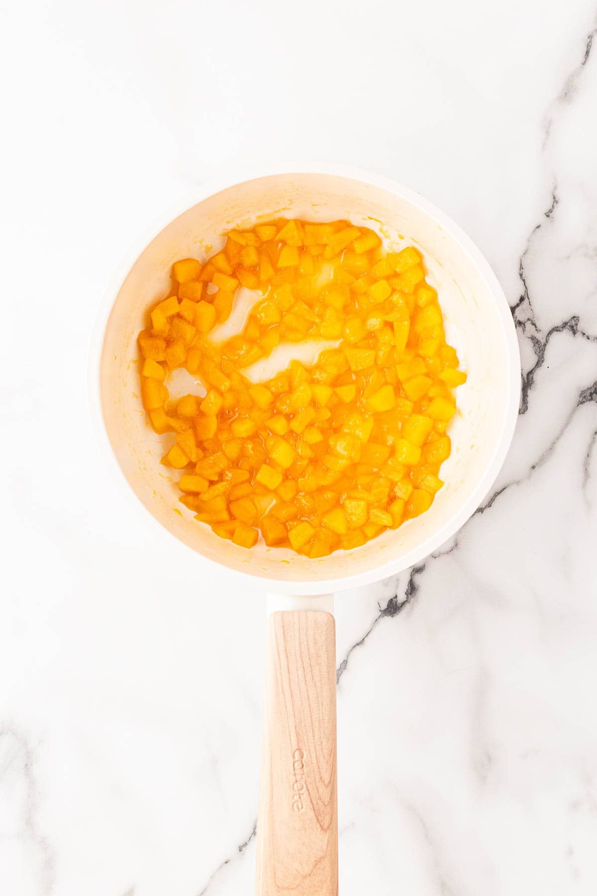 Diced peaches cooking down in a saucepan until soft and juicy