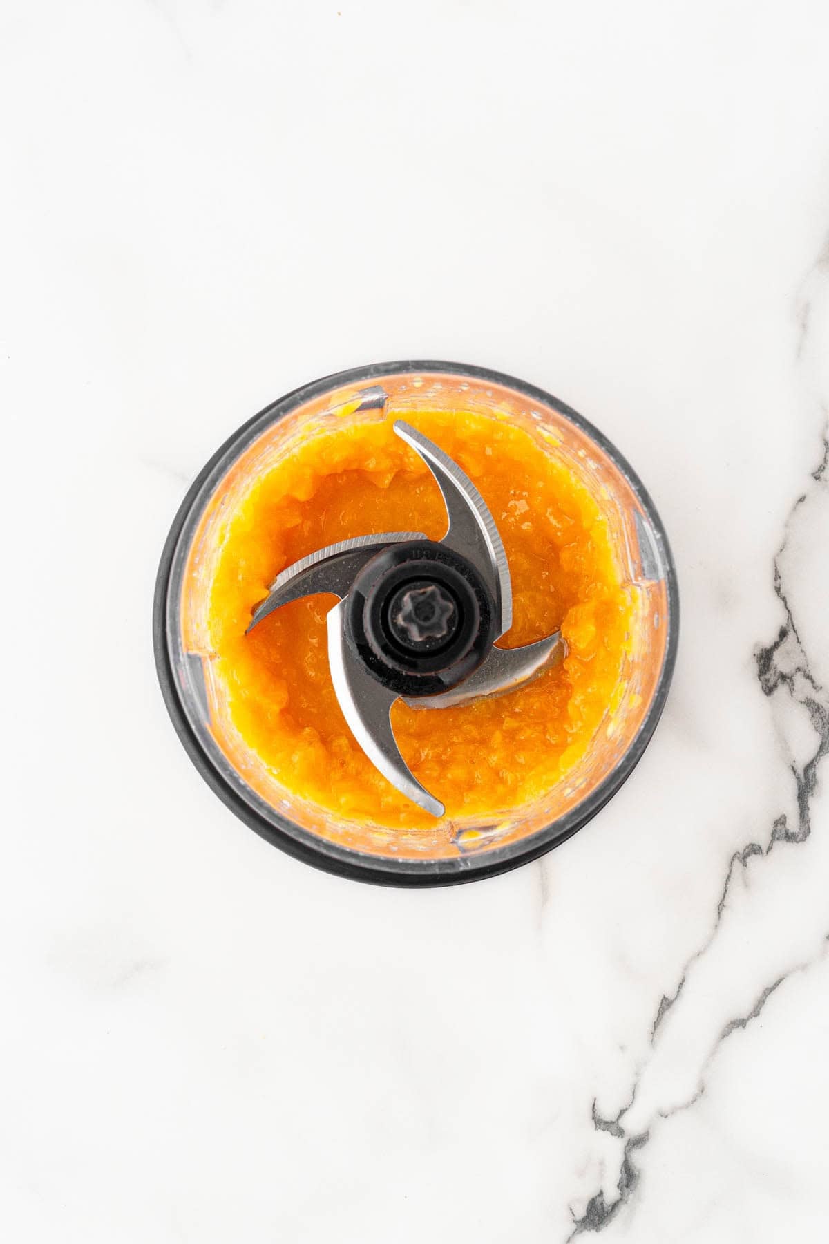 Cooked peaches blended into a chunky peach puree in a food processor