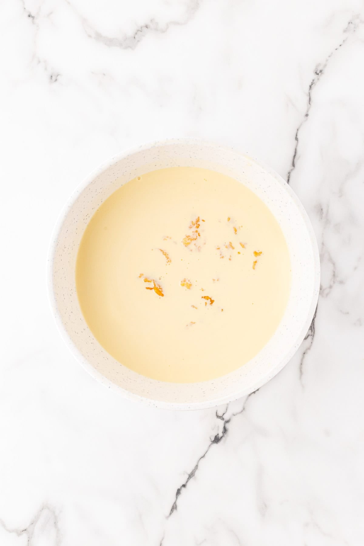 Custard base mixed vanilla extract, bourbon, and cooled peach puree in a white bowl