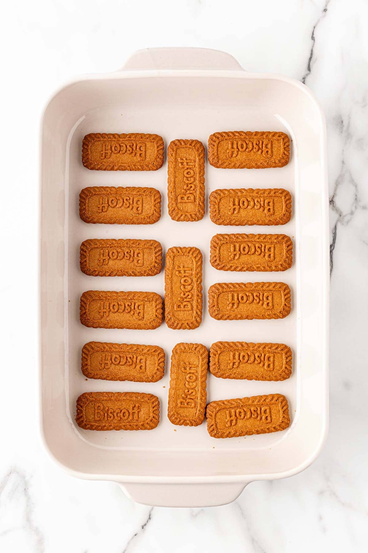 Biscoff cookies arranged in a baking dish on a white marble background