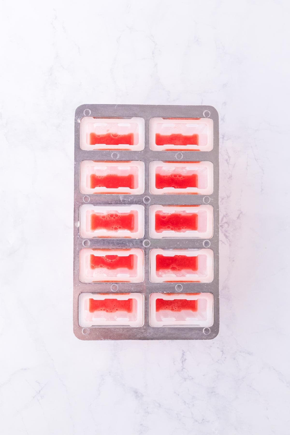 Popsicle mold cavities partially filled with watermelon puree