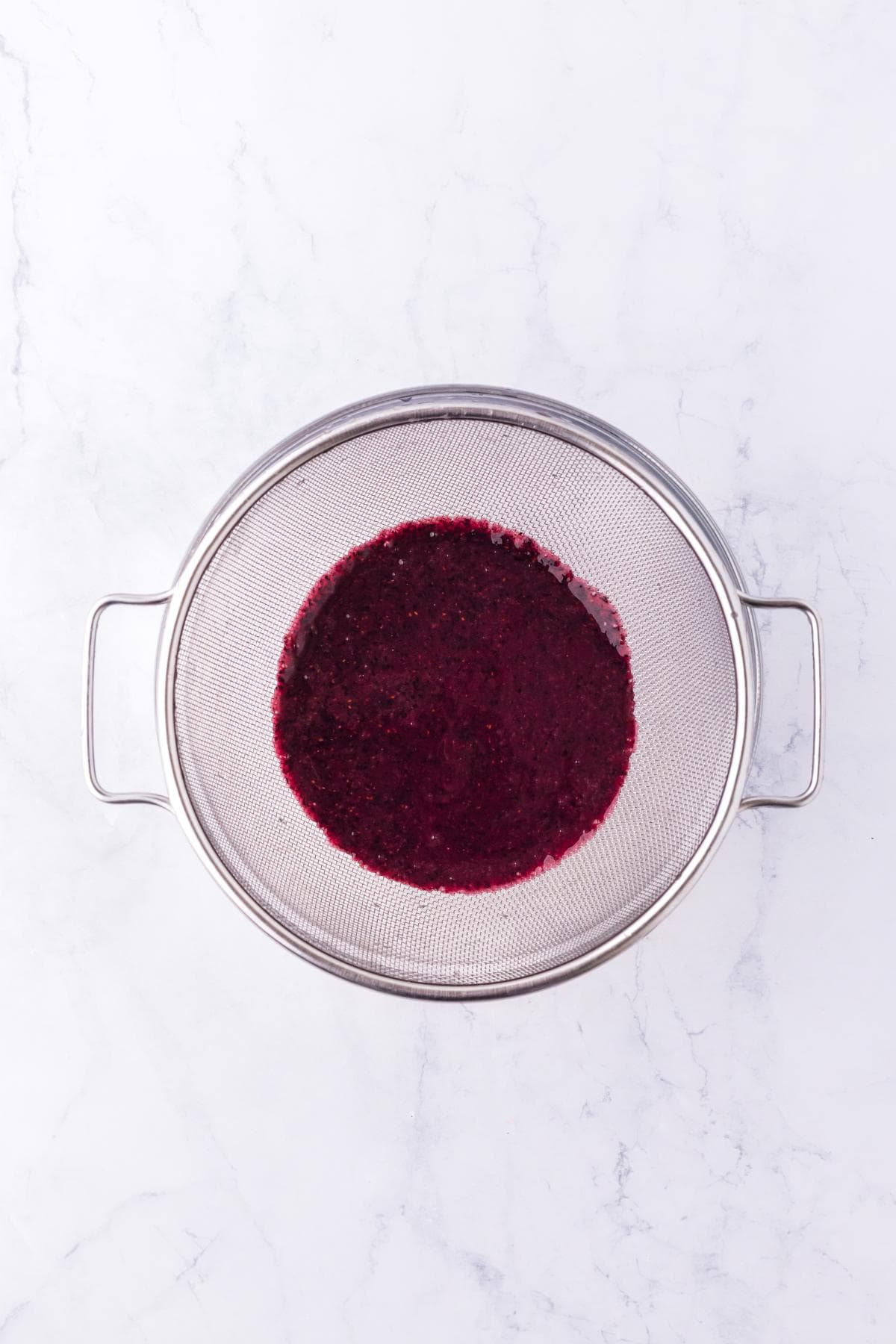 Strained blueberry puree in a fine mesh sieve
