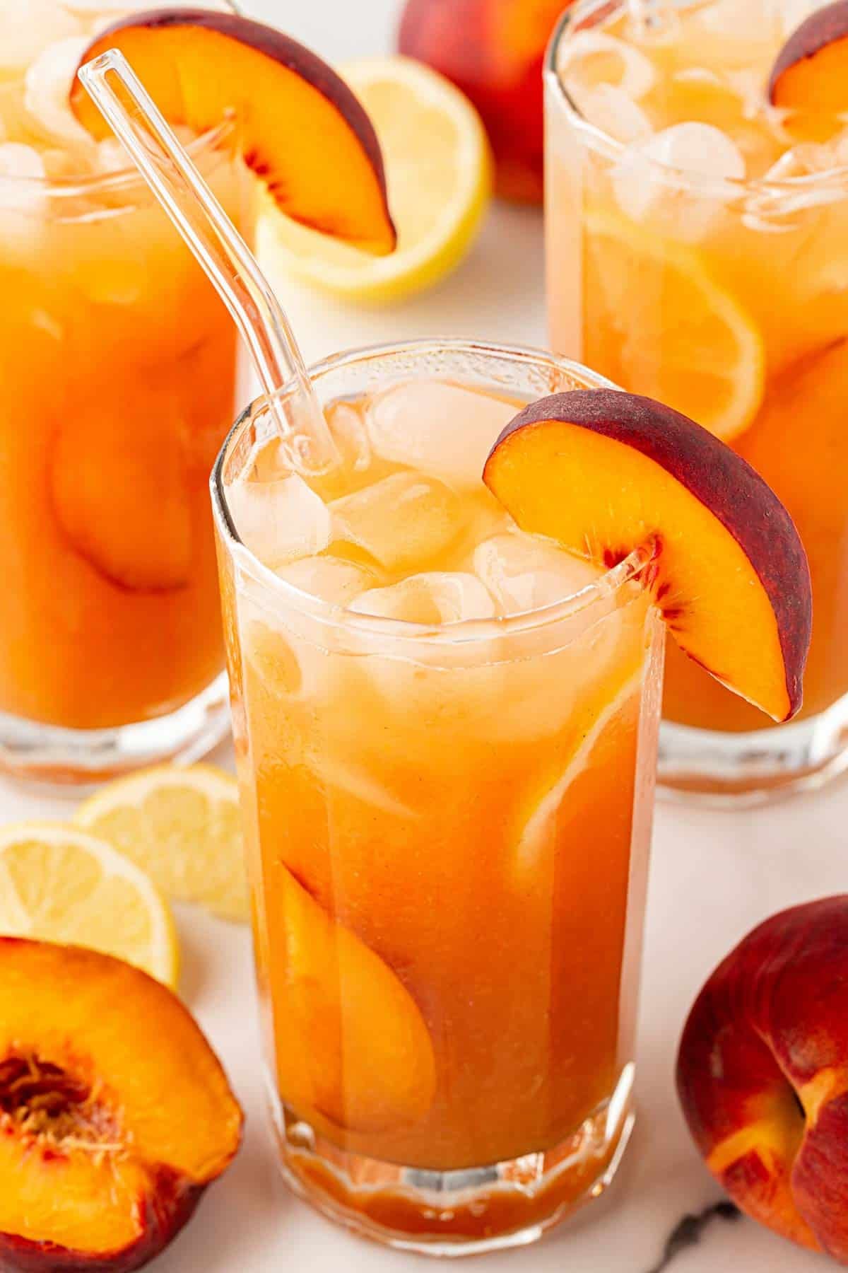 peach cobbler lemonade with peach slices and ice in a tall glass.