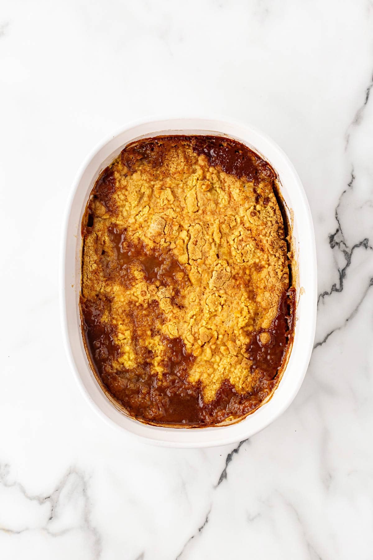 Freshly baked peach dump cake with a golden brown topping in a baking dish