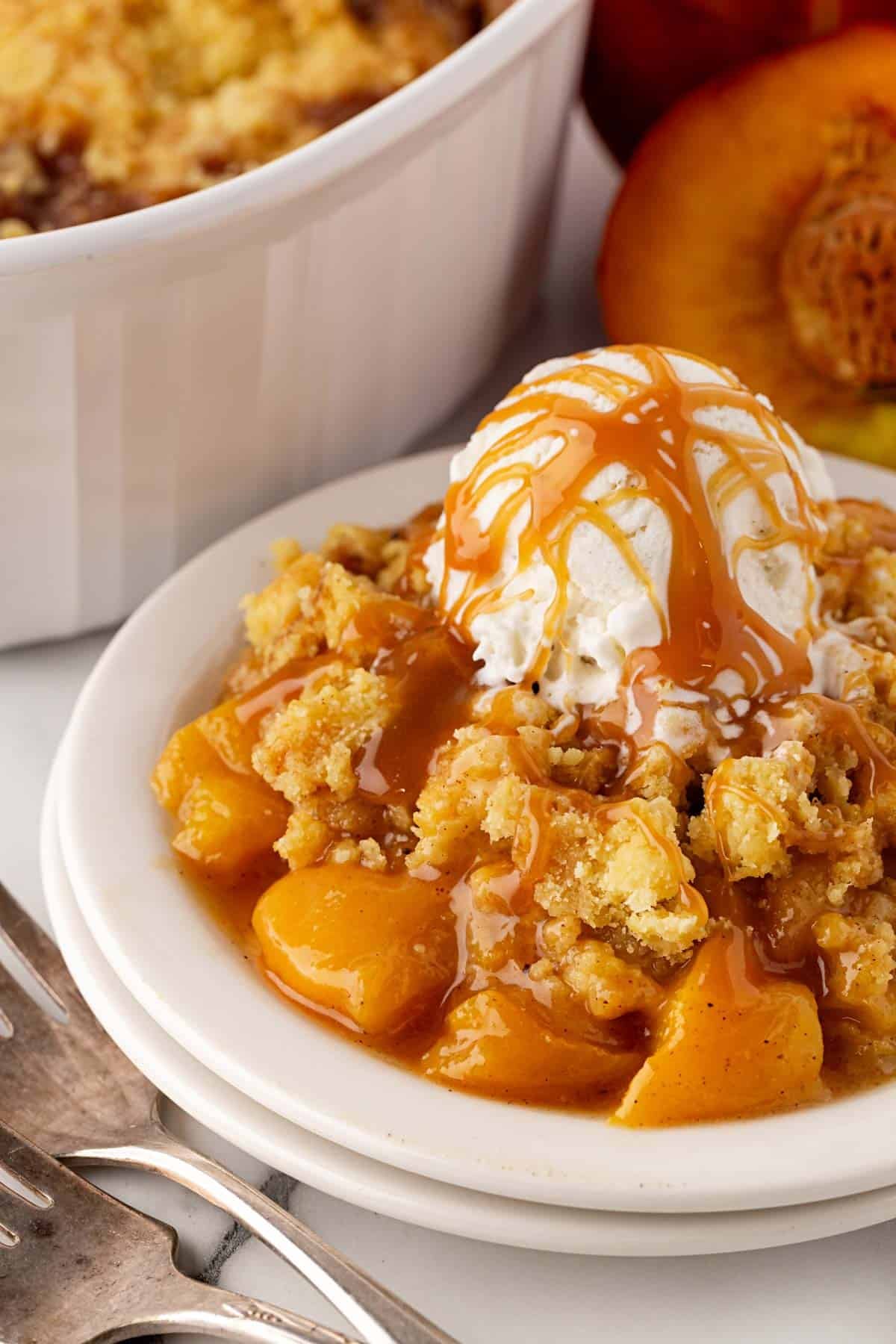Peach dump cake topped with vanilla ice cream and caramel sauce, served in a white bowl