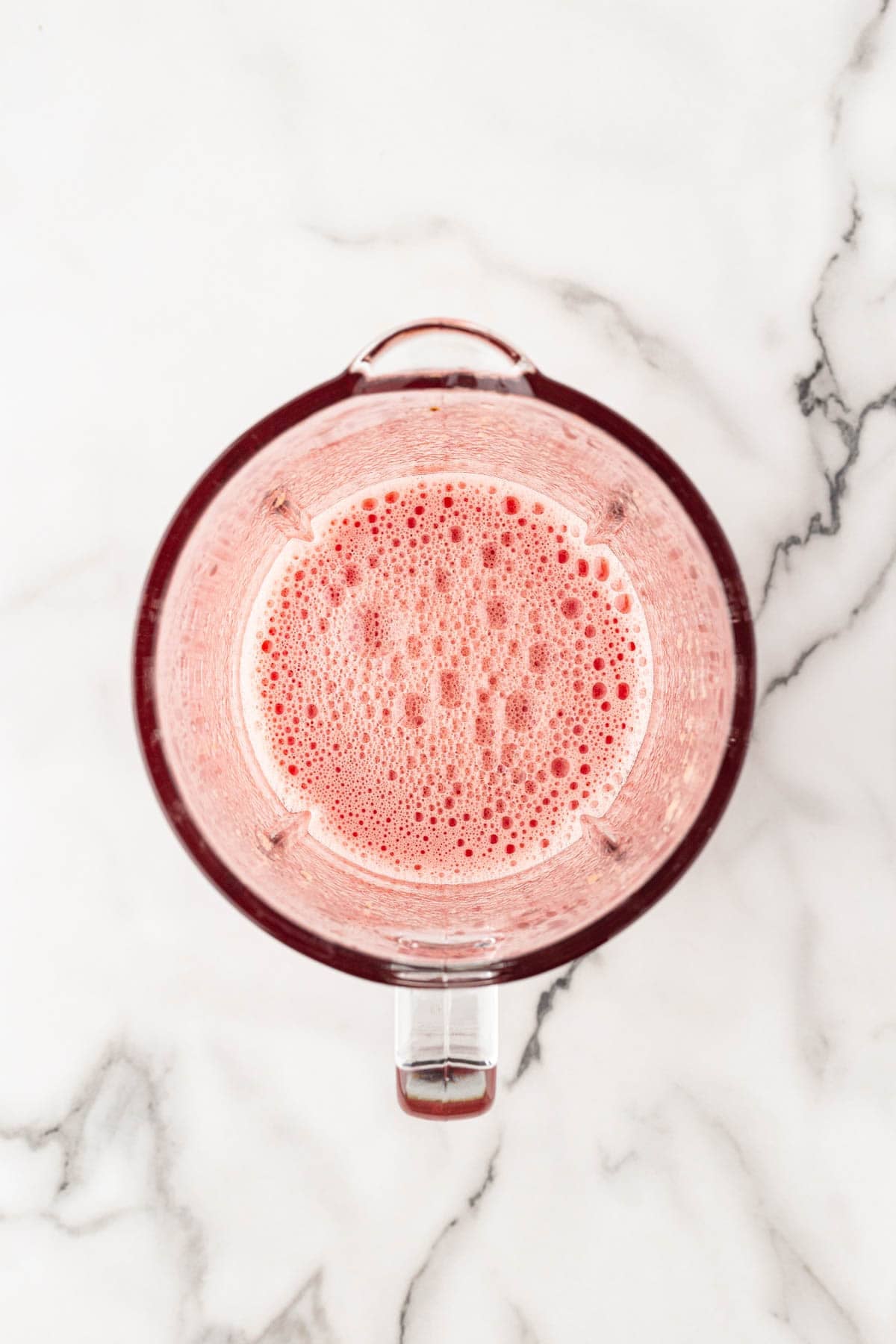 Smooth watermelon puree inside a blender on a white marble countertop after blending