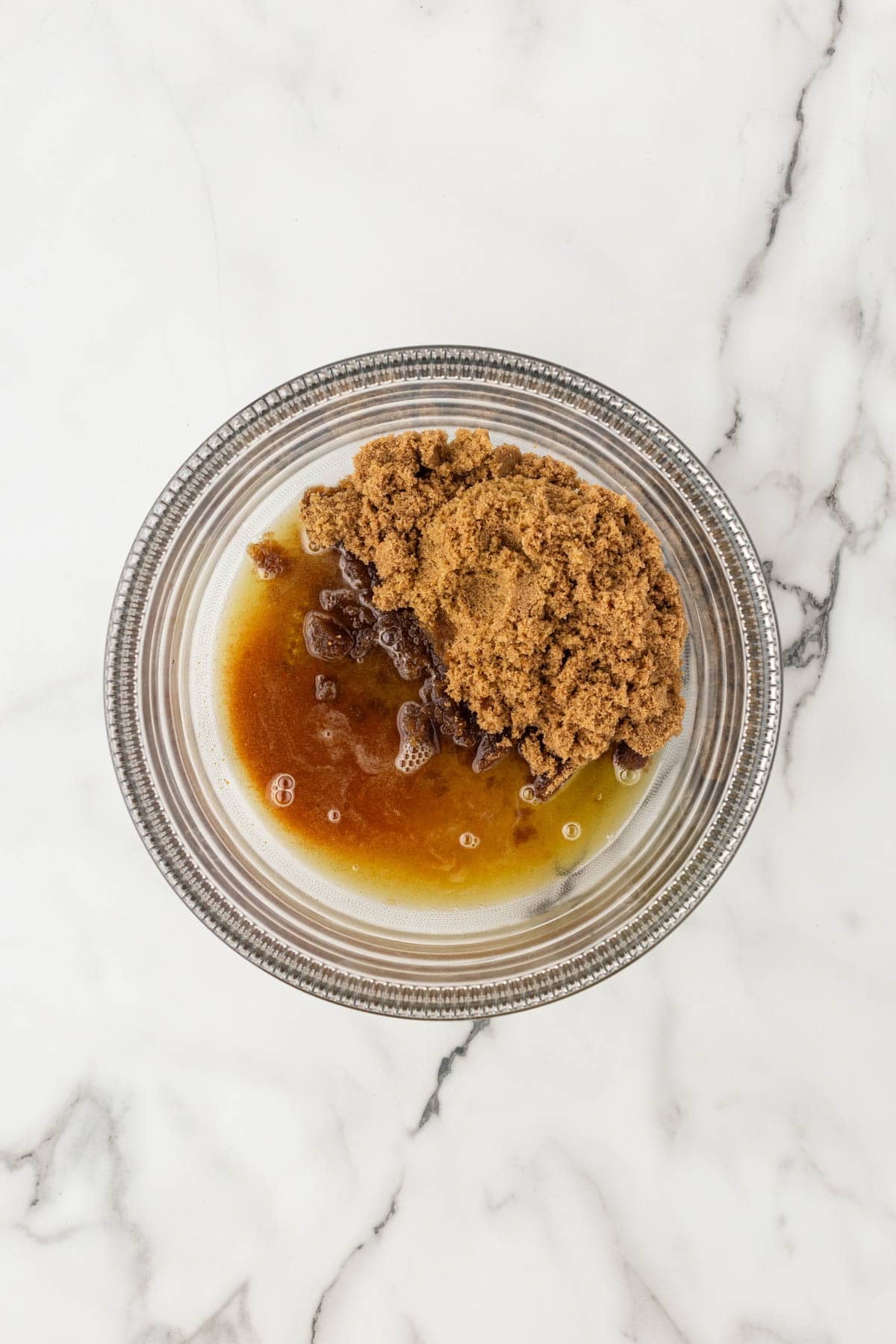 Brown sugar and melted butter in a glass mixing bowl