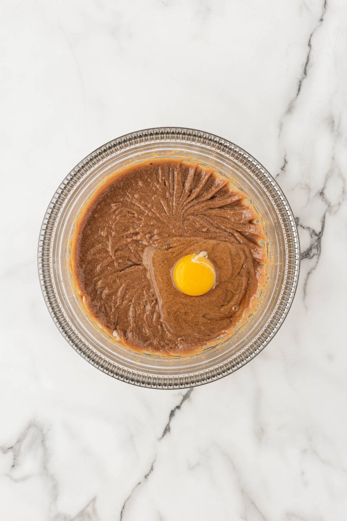 Egg added to the butter and brown sugar mixture in a glass bowl