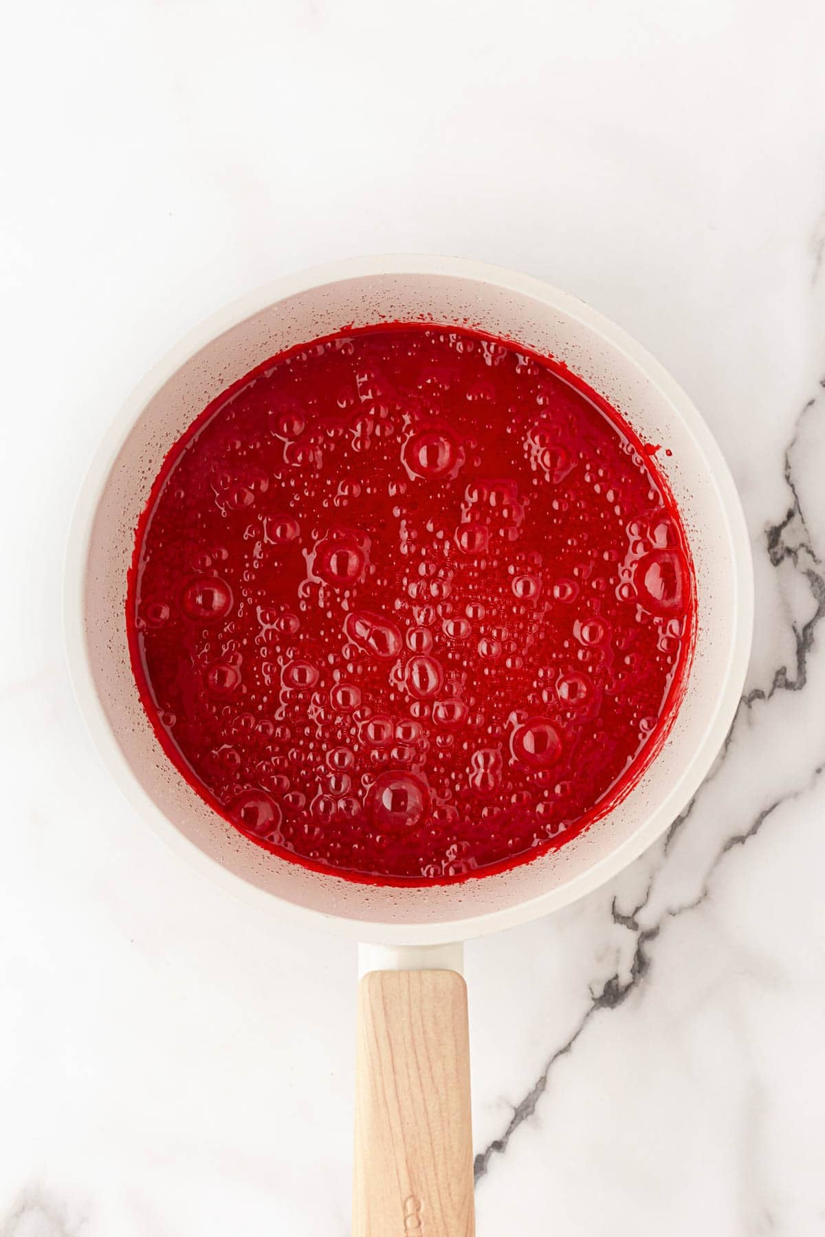 Red candy coating bubbling in a saucepan