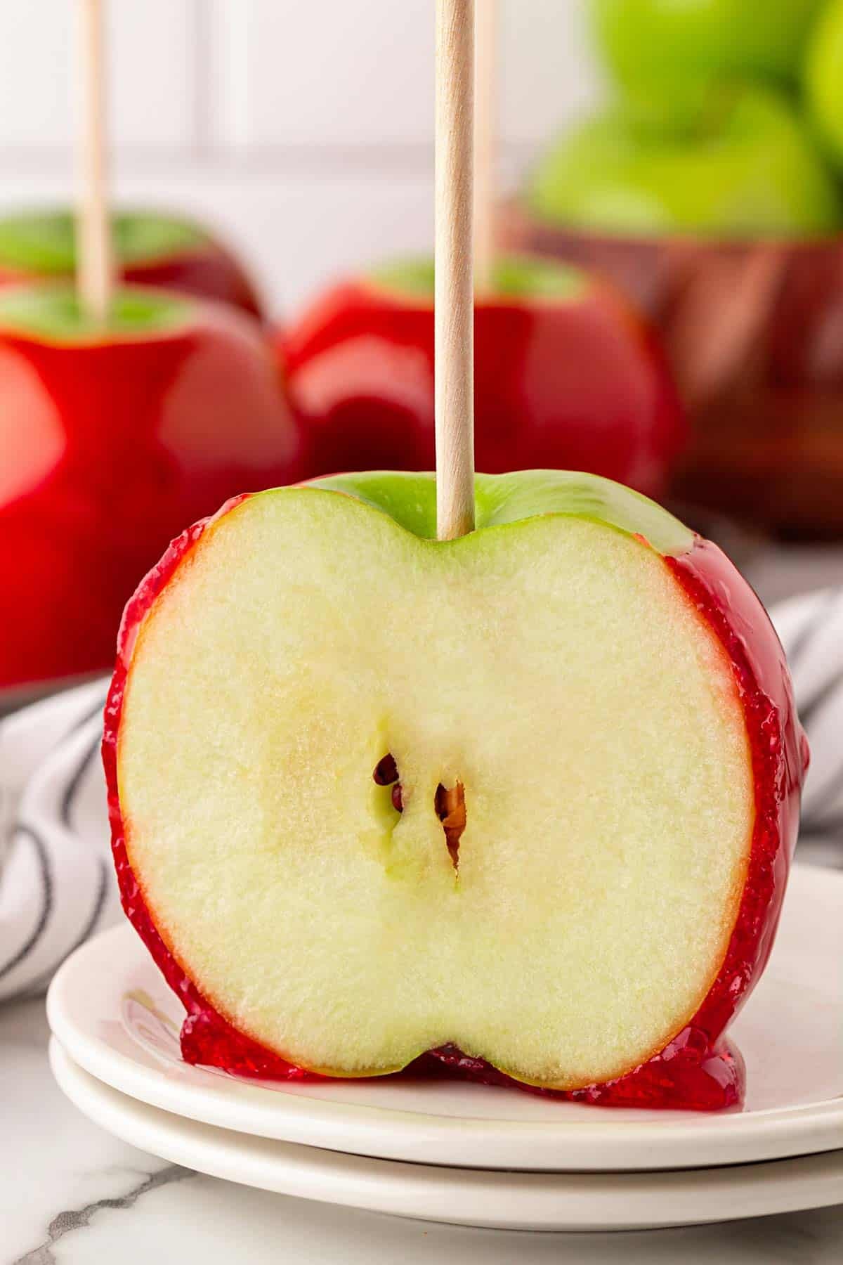 Halved candied apple showing the crisp green apple inside the red candy shell