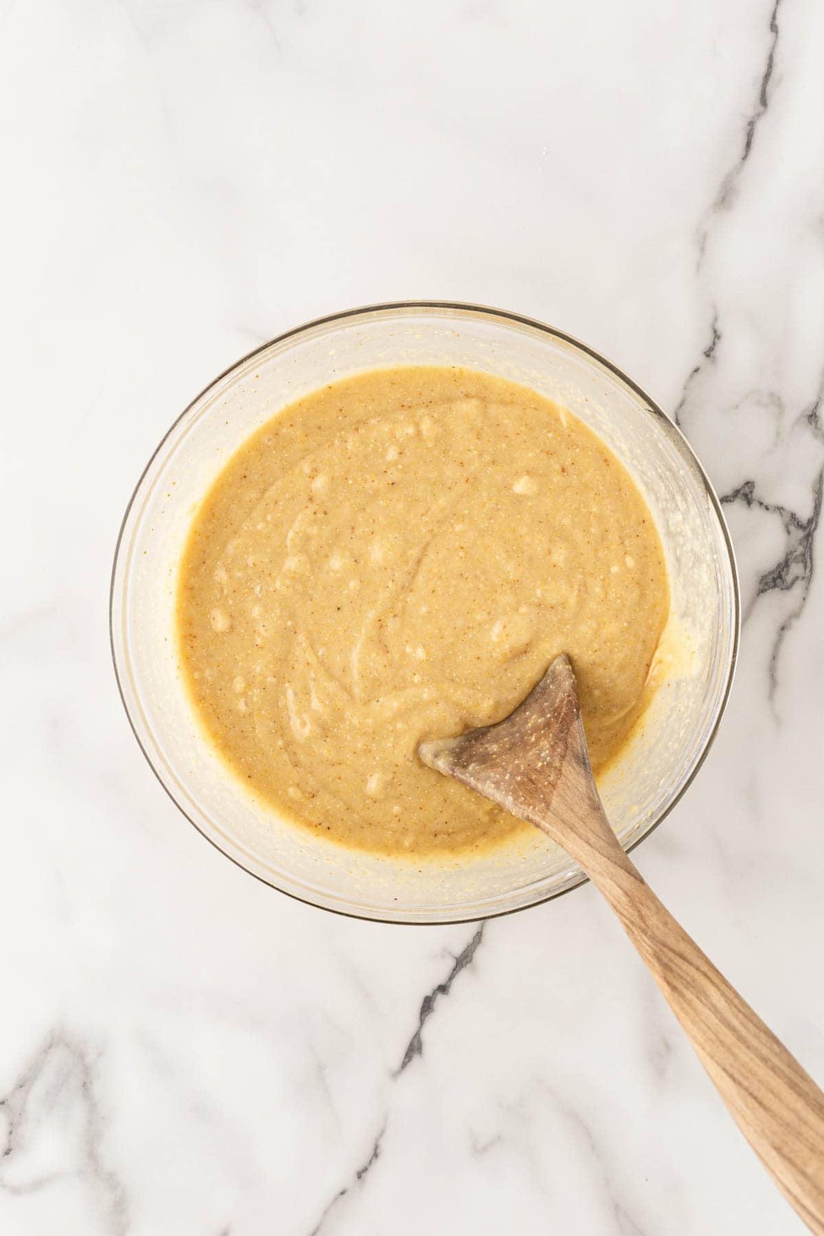 Honey butter cornbread batter mixed in a glass bowl