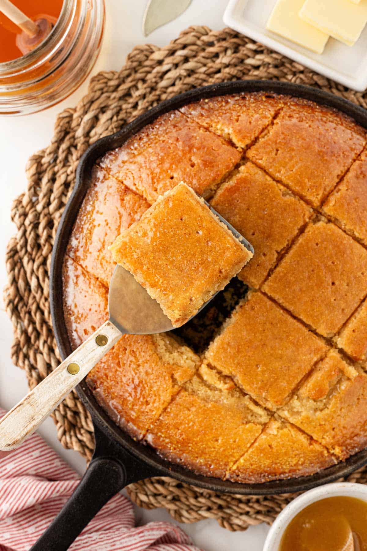 Square of honey butter cornbread lifted from a cast iron skillet