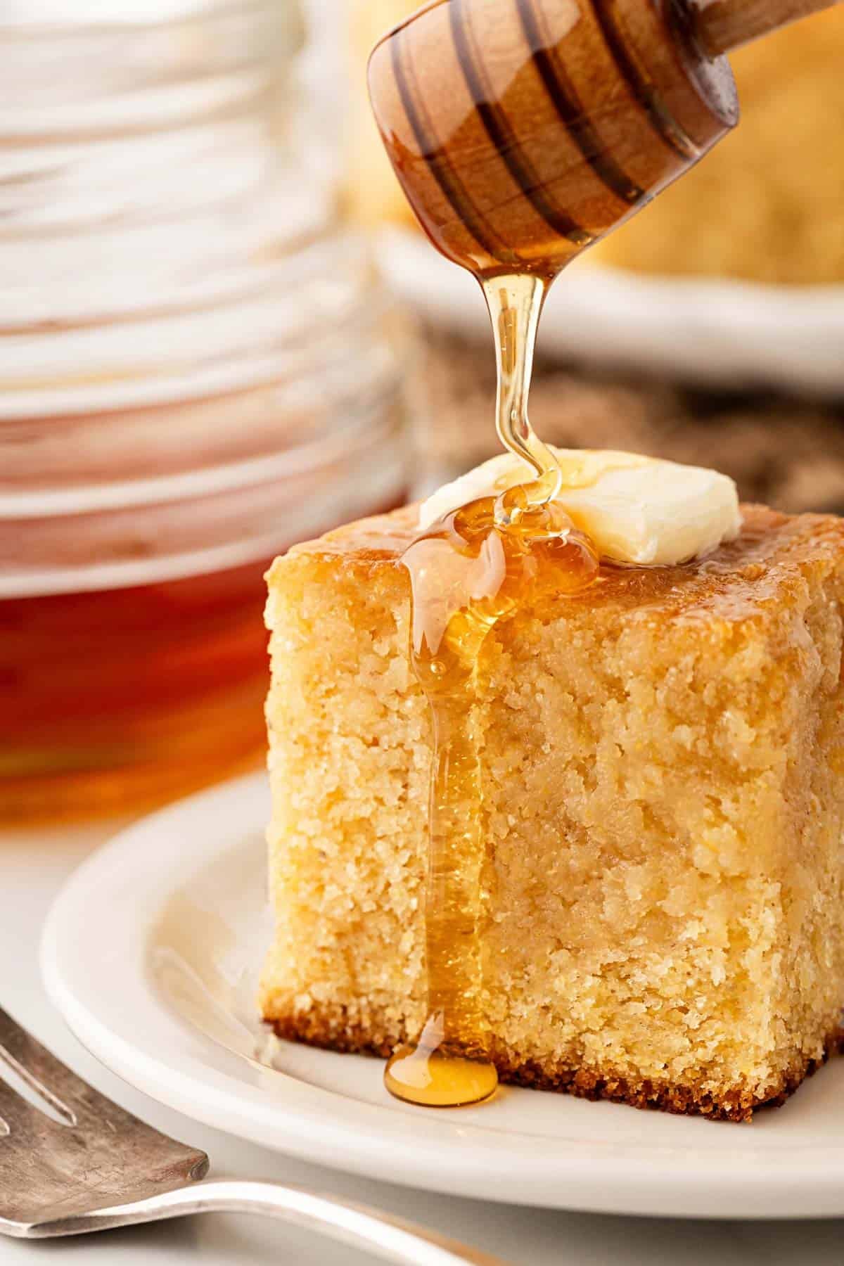 Honey drizzled over a slice of honey butter cornbread with butter