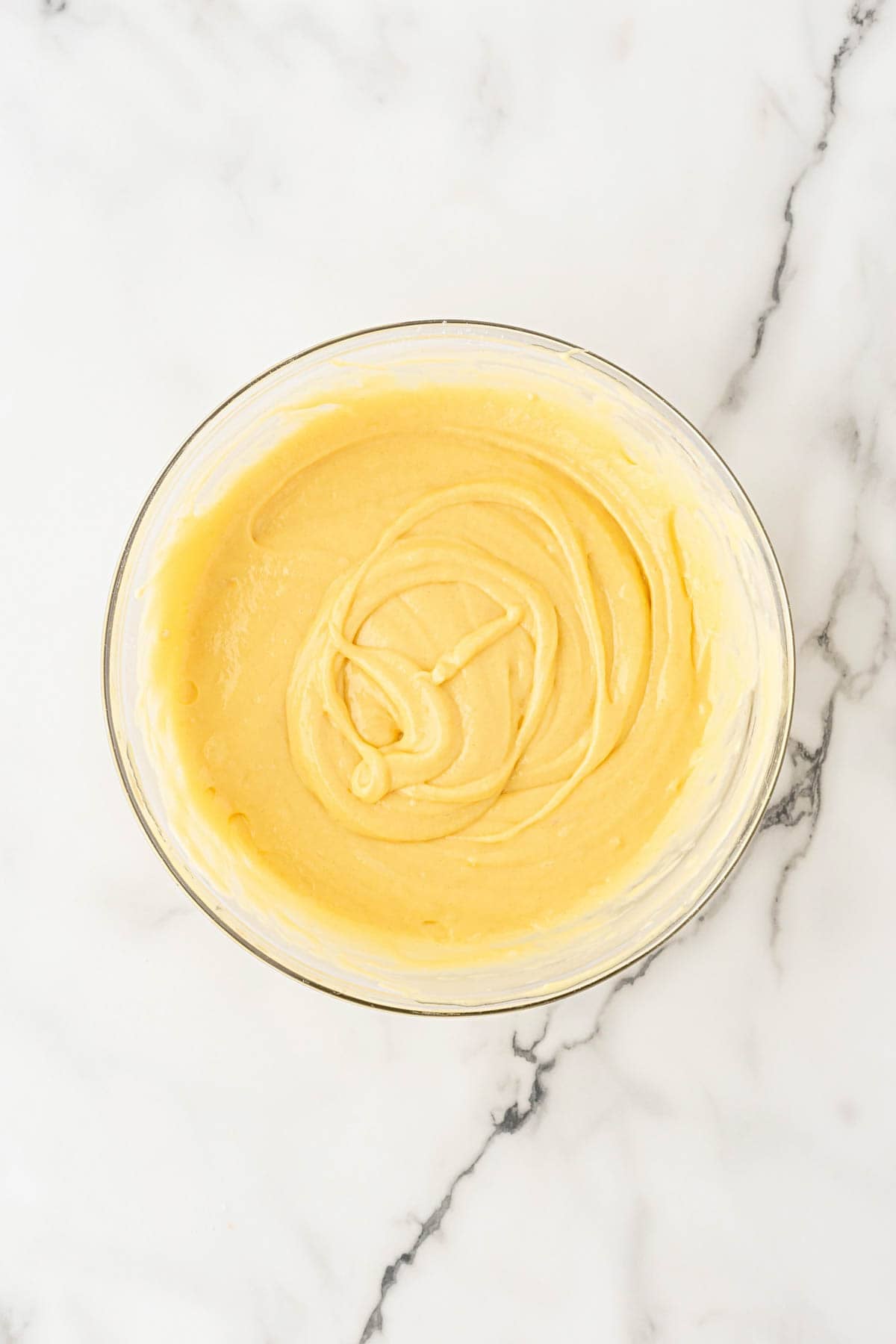 Yellow cake batter mixed in a glass bowl