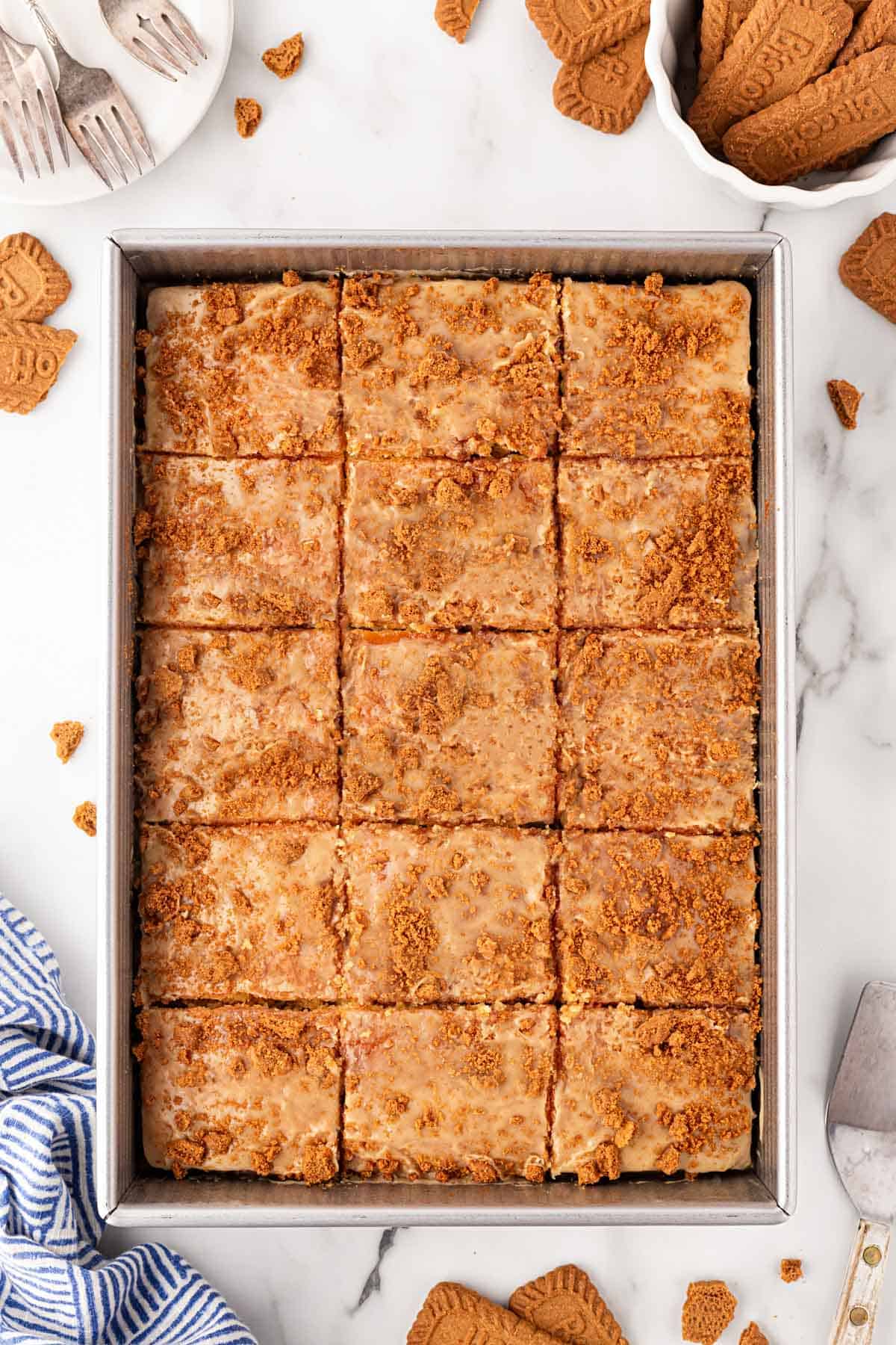Biscoff honey bun cake cut into squares and topped with cookie crumbs