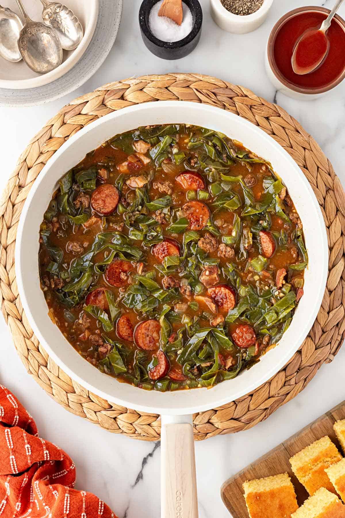 Cooked dirty greens with andouille sausage, ground beef, and bacon in a skillet