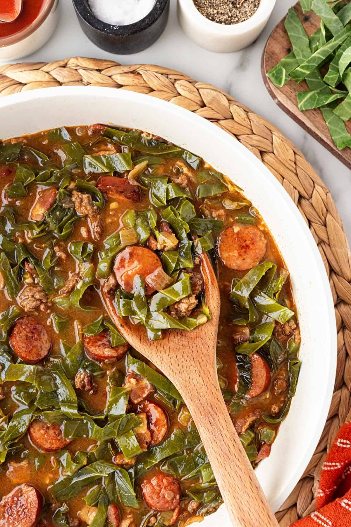 Dirty greens with sausage, ground beef, and bacon served with cornbread and hot sauce