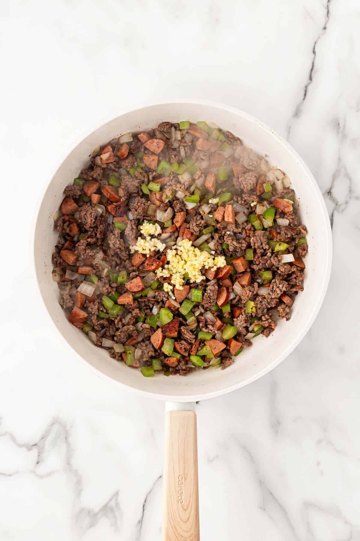 Ground beef and andouille sausage cooked with diced onion and green bell pepper, with minced garlic added
