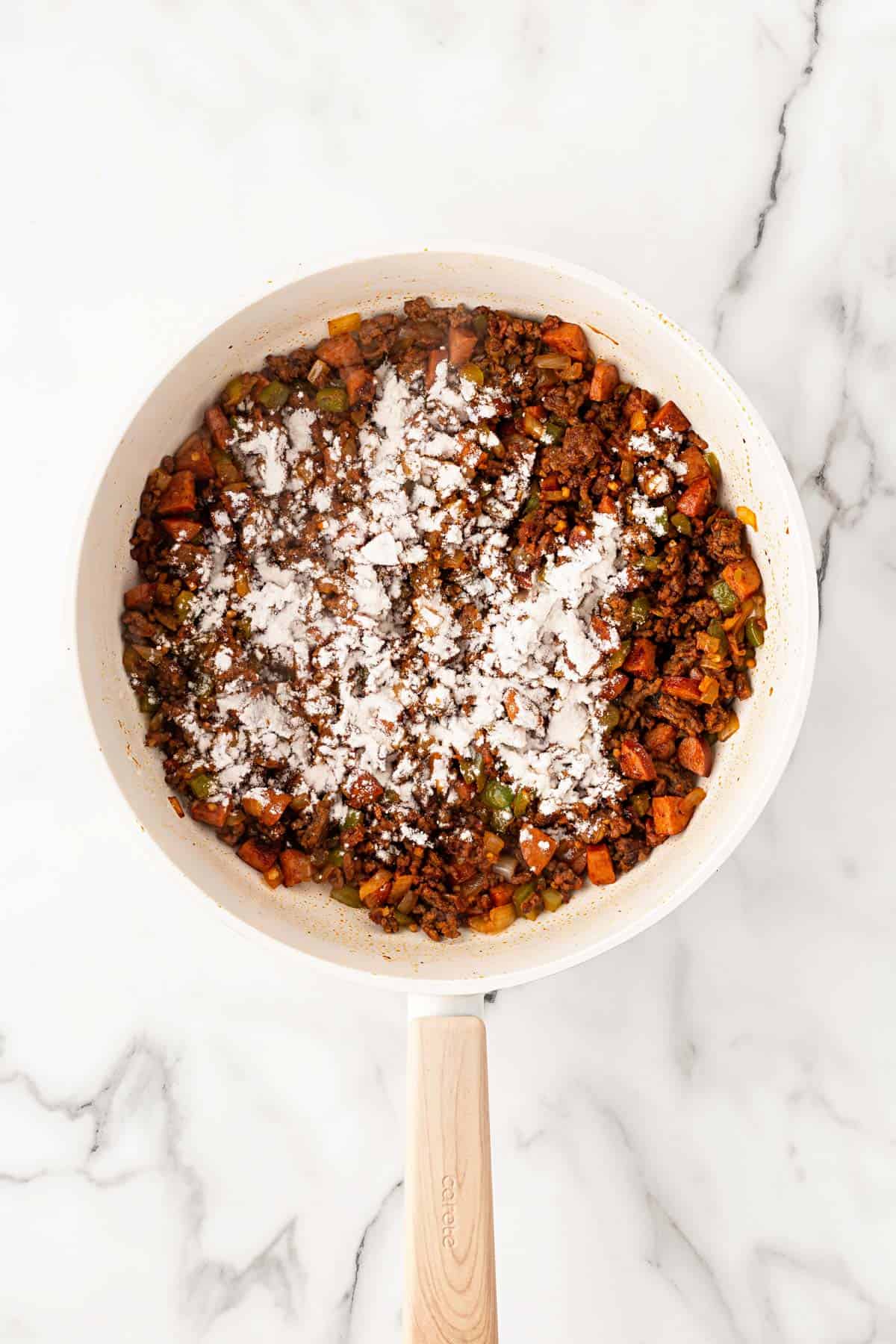 Ground beef, andouille sausage, peppers, and onions coated in tomato paste and sprinkled with flour