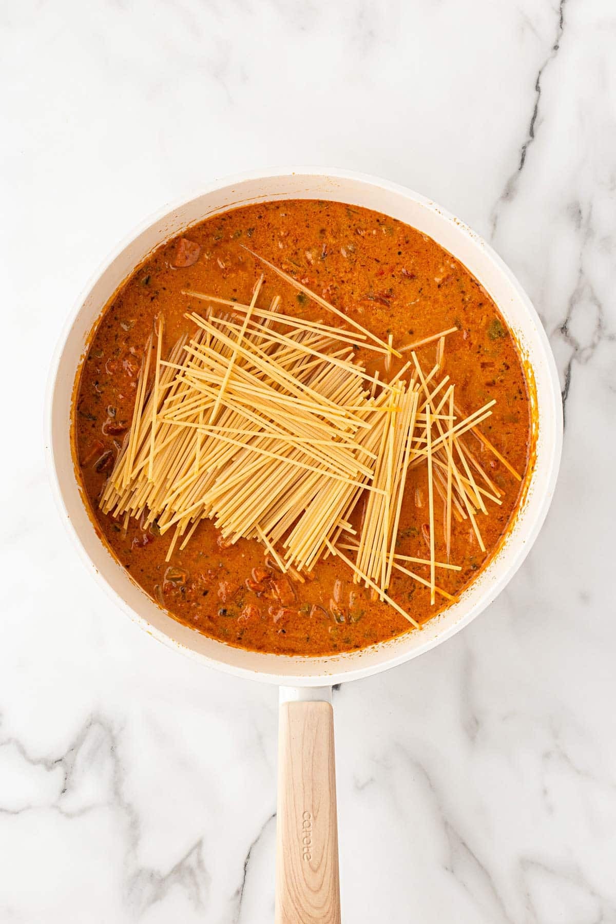 Broken spaghetti added directly to the creamy Cajun meat sauce in a large skillet