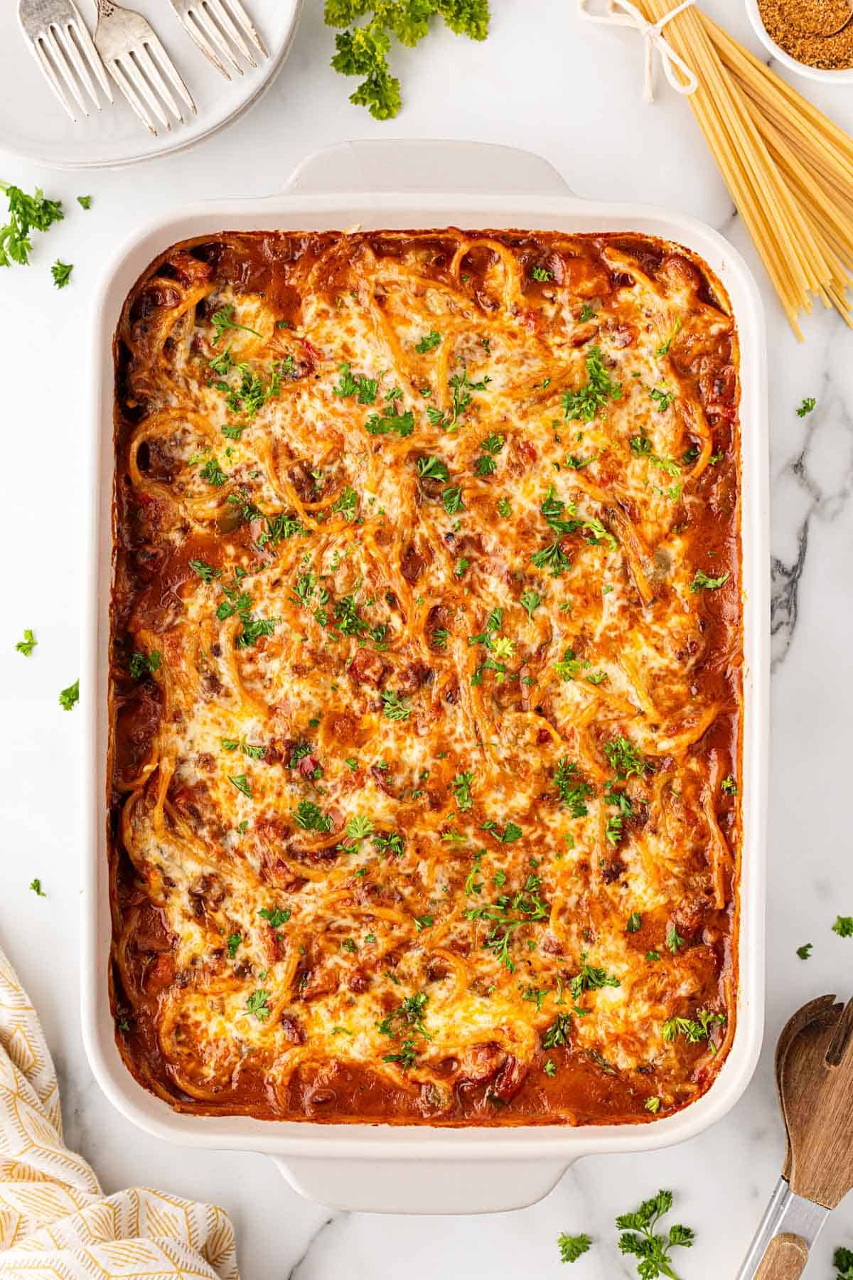 Baked dirty spaghetti with golden melted cheese and chopped parsley in a casserole dish