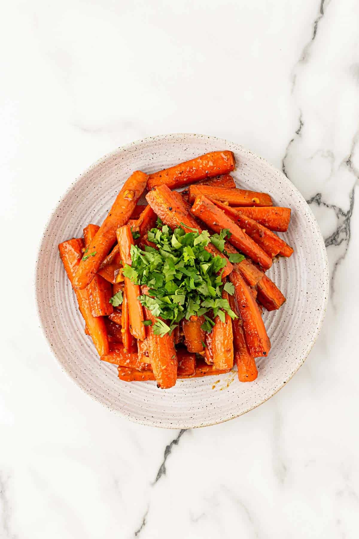 Glazed roasted carrots piled on a plate and topped with fresh chopped cilantro