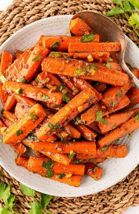 Overhead shot of glazed roasted carrots with peanut maple sauce, chopped peanuts, and fresh cilantro