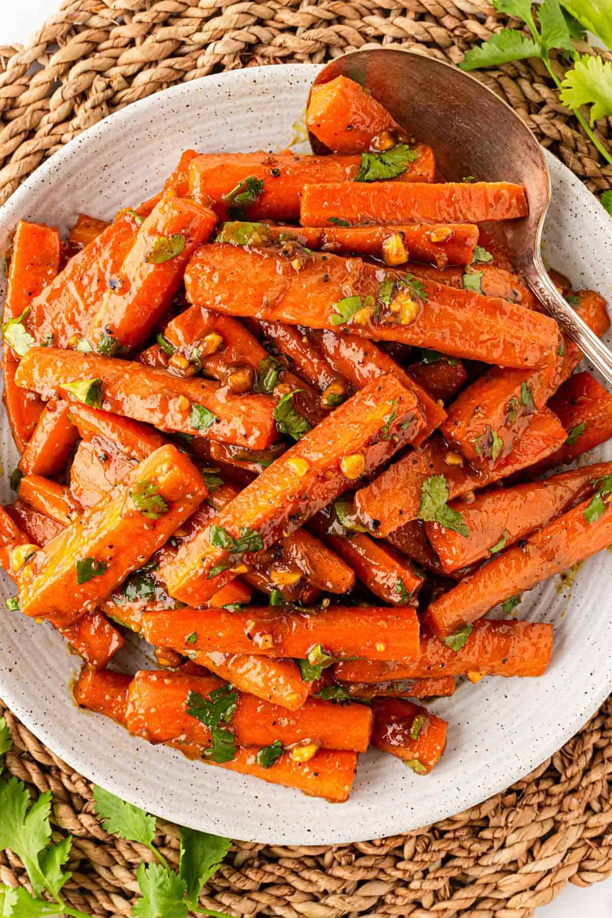 Overhead shot of glazed roasted carrots with peanut maple sauce, chopped peanuts, and fresh cilantro