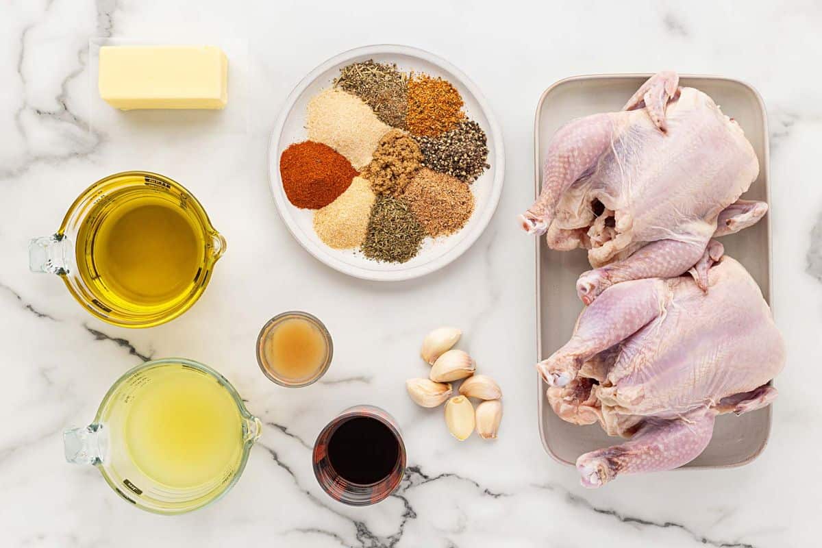 Overhead shot of ingredients for making Cornish hens on a marble surface