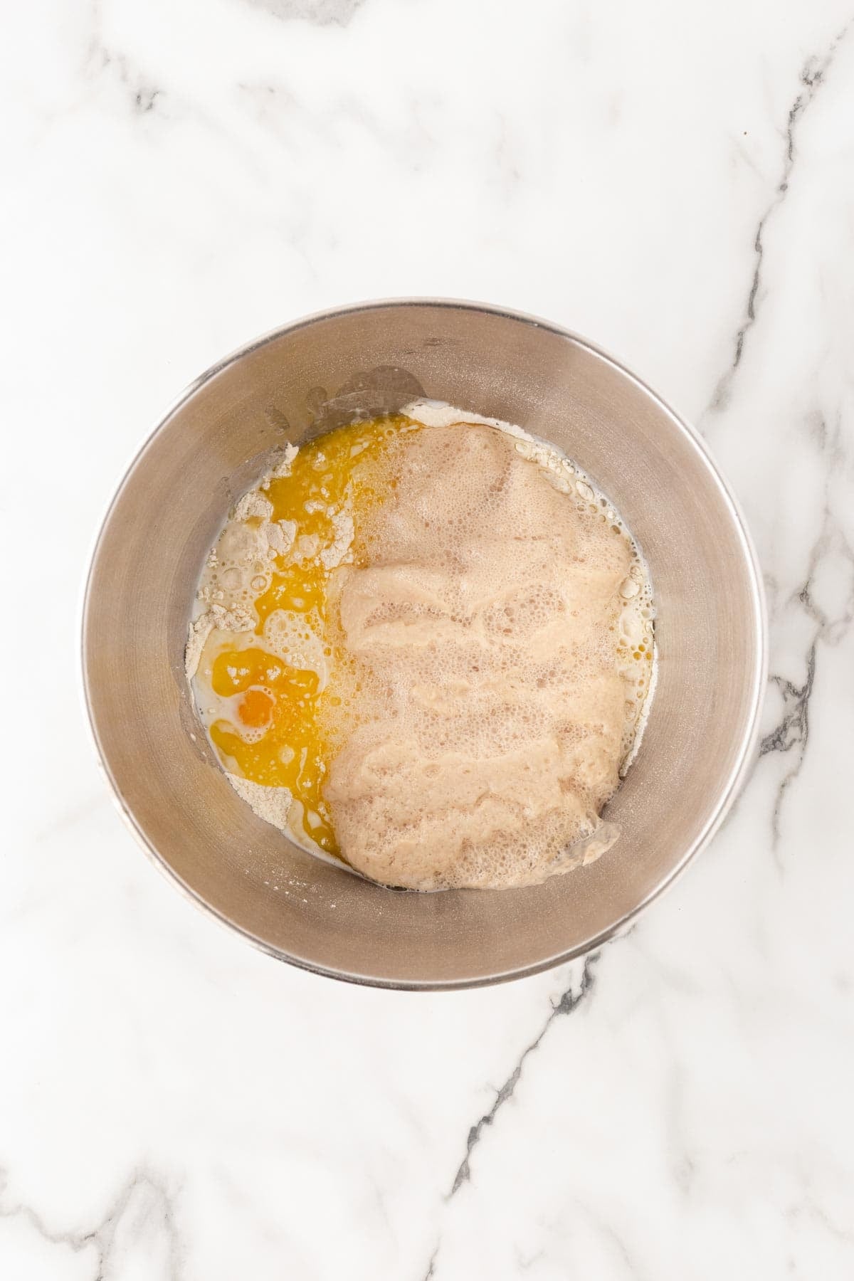Cinnamon roll dough ingredients coming together in a metal mixing bowl