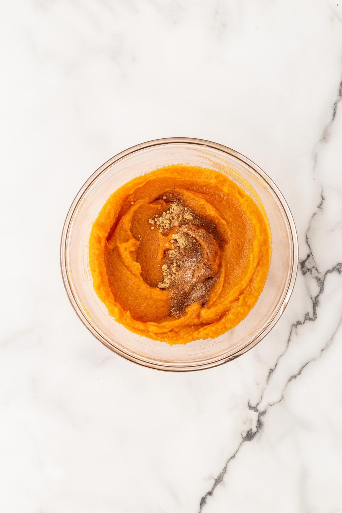 Mashed sweet potato with butter and spices in a glass bowl