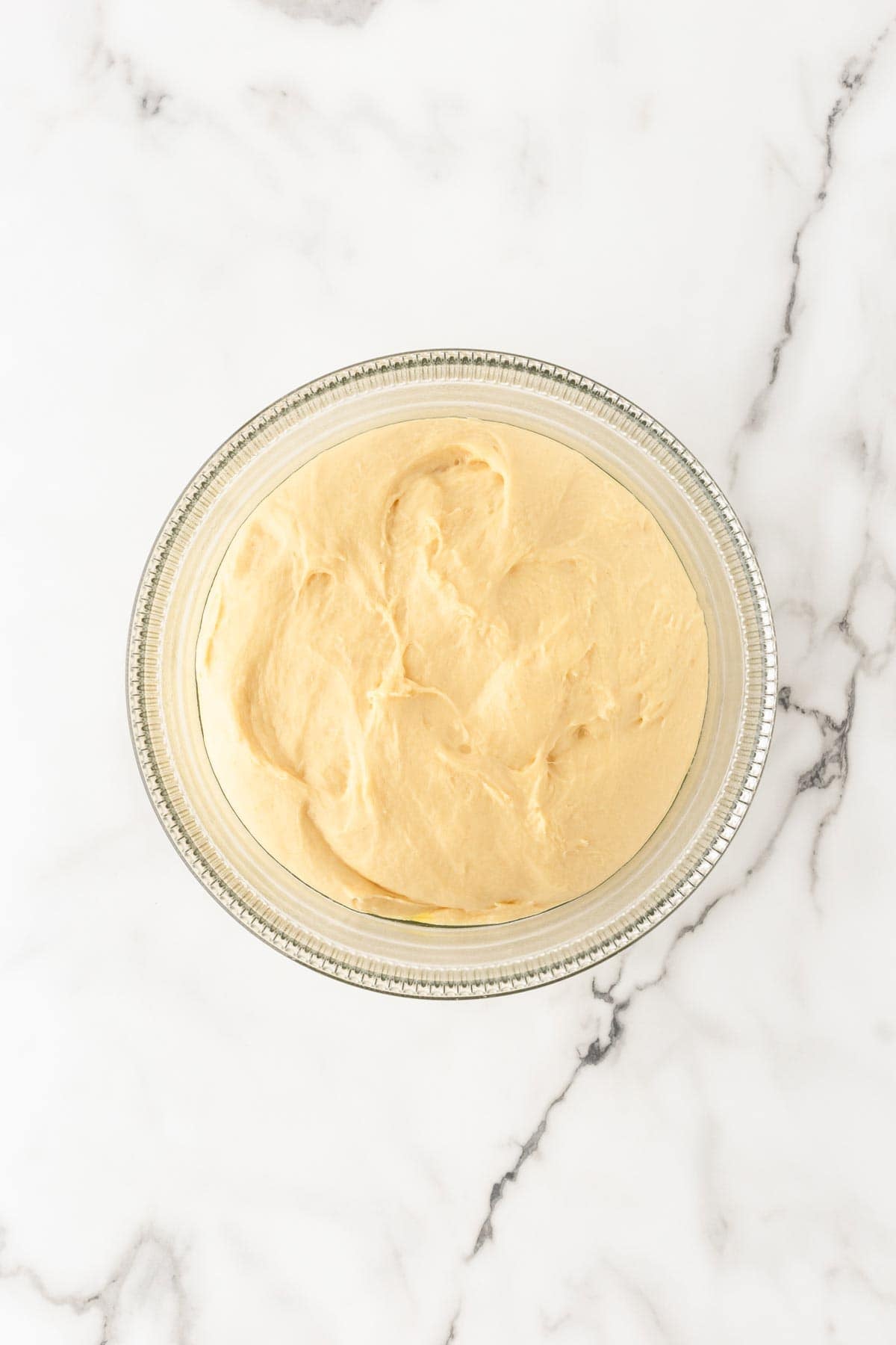 Smooth risen cinnamon roll dough in a glass bowl